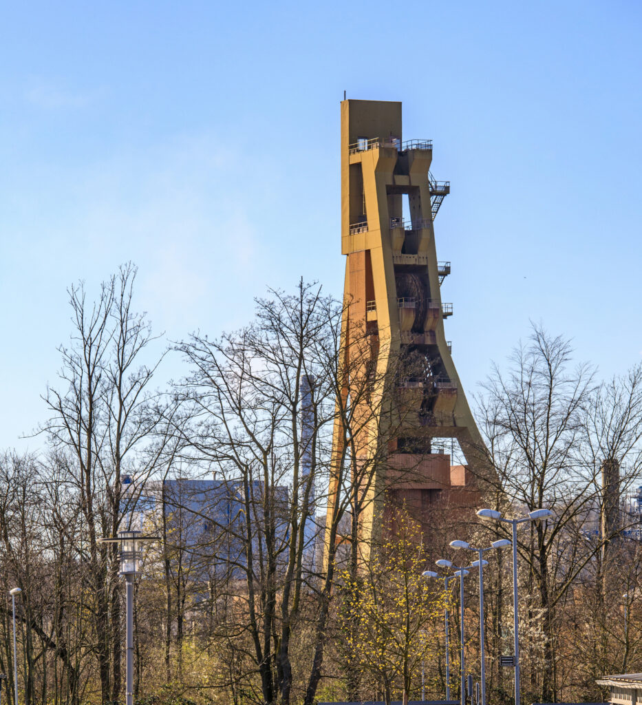 Industriekulisse der Zeche Bergkamen, eingerahmt von laublosen Bäumen im Vordergrund.